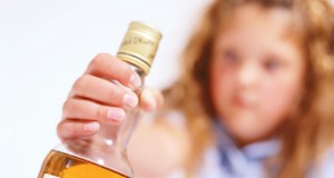 blurred view of a young girl (6-8) holding a bottle of scotch whisky